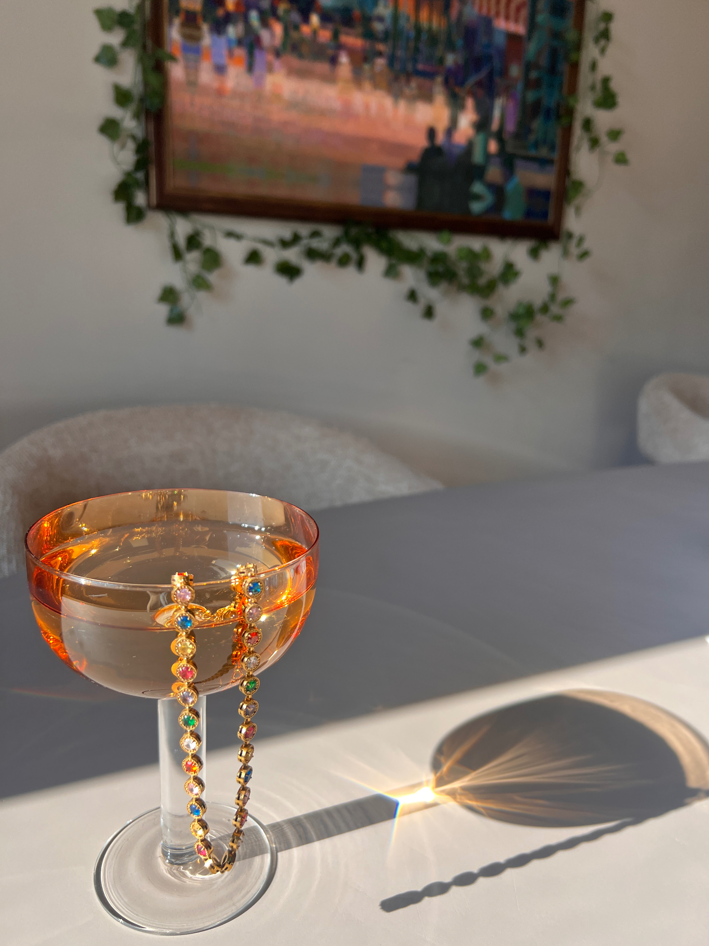 Kleurrijke armband met steentjes over een coupe glas in de middagzon