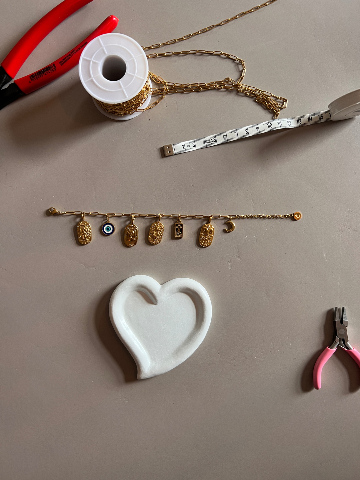 Bedelarmband in de maak op de werktafel in Groningen, met tangen en meetlint