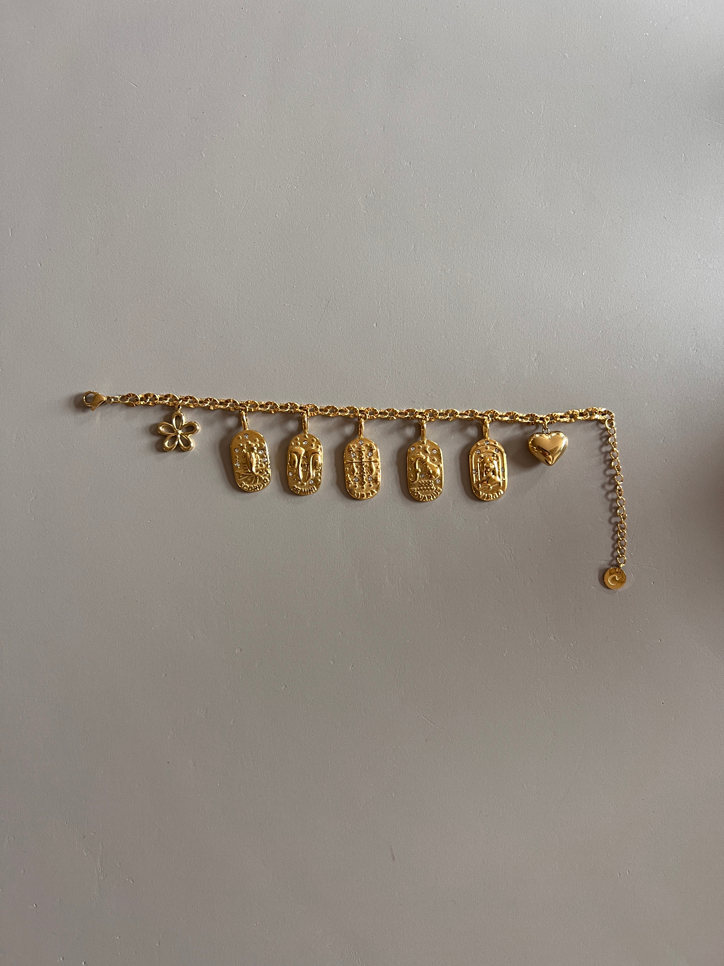 Afgemaakte gouden bedelarmband met bedels, hartje en bloem